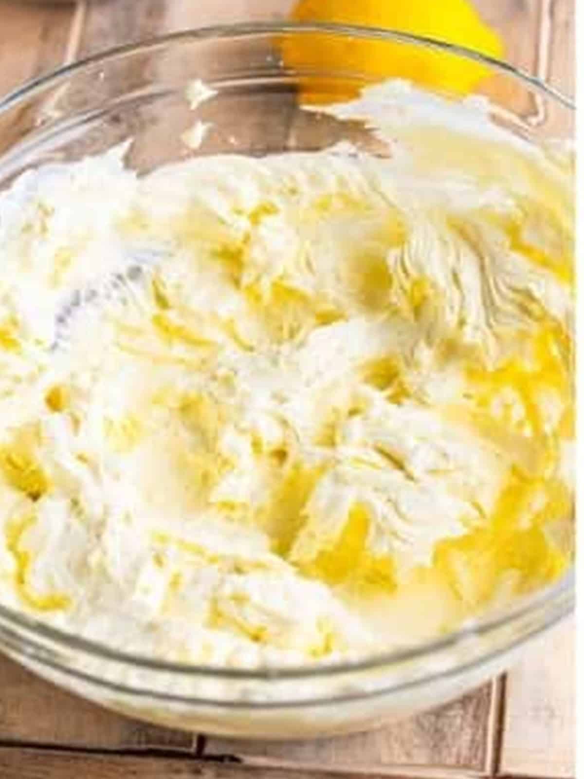 Cream cheese whipped until smooth in a large glass bowl for No Bake Blueberry Cheesecake filling.