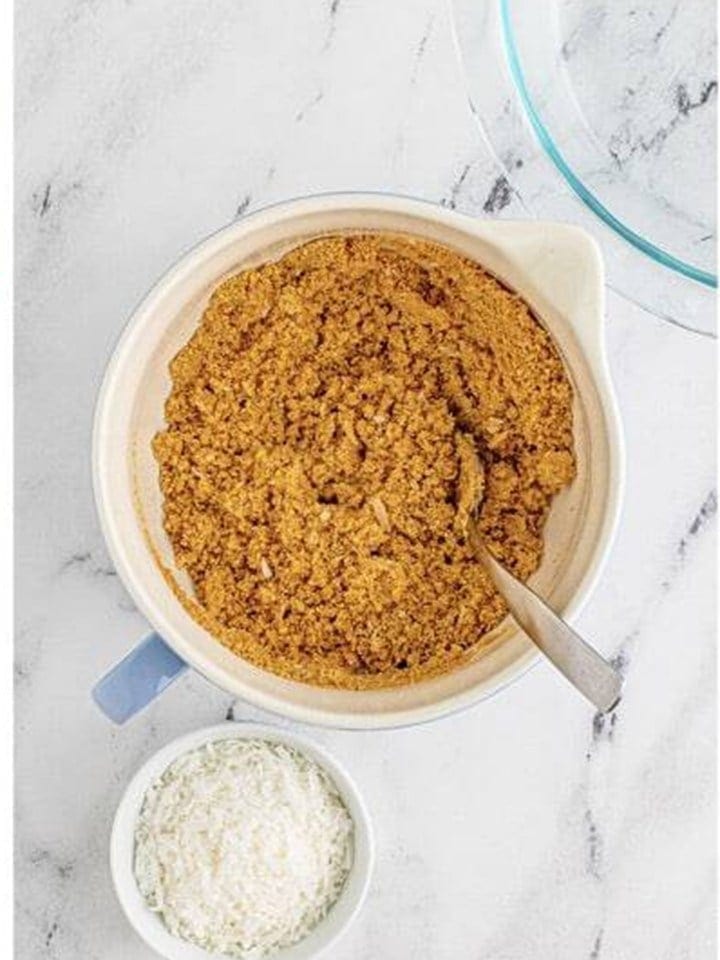 The coconut graham cracker crust mixture stirred together in the bowl.