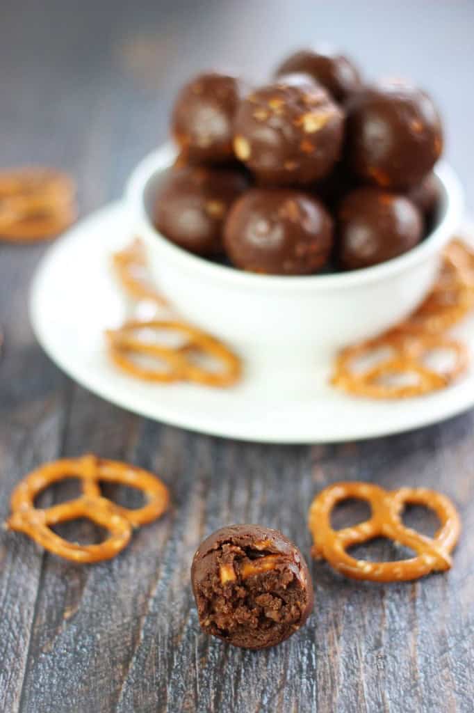 Rolled Nutella truffles in a bowl with one truffle and pretzels in front.