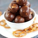 Nutella truffles stacked in a small white bowl surrounded by pretzel twists.