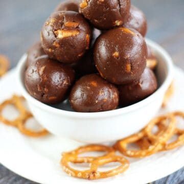 Nutella truffles stacked in a small white bowl surrounded by pretzel twists.