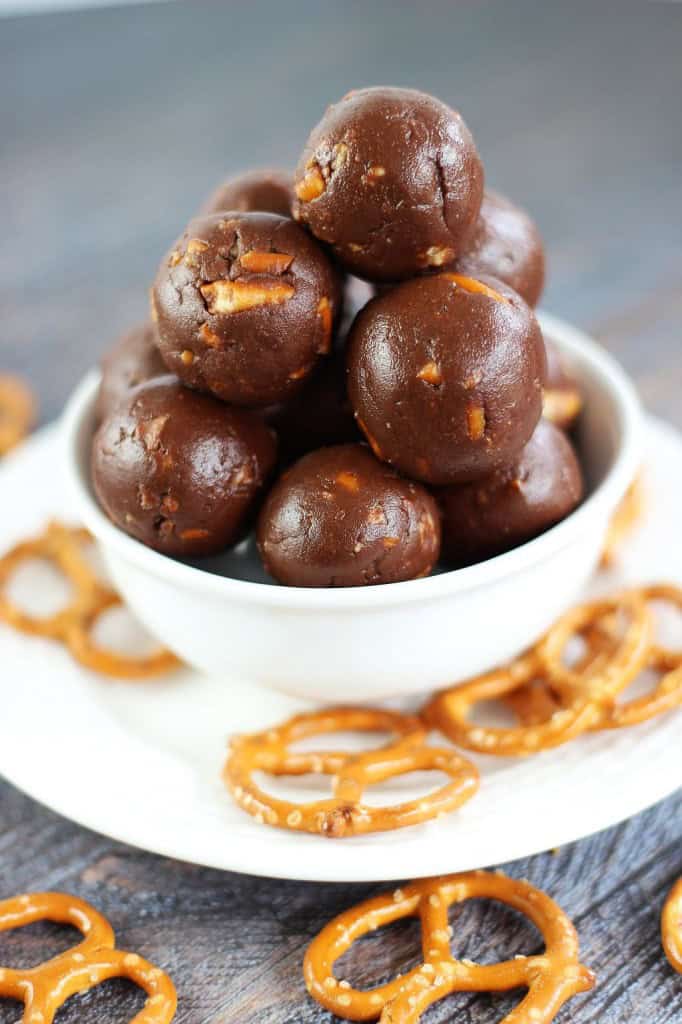 Nutella truffles stacked in a small white bowl surrounded by pretzel twists.