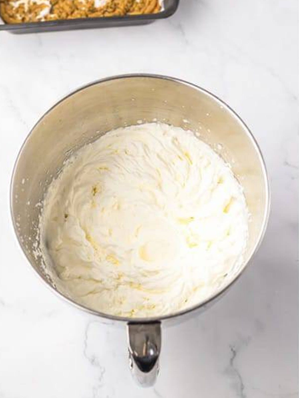 Heavy cream whipped to stiff peaks in a mixing bowl.