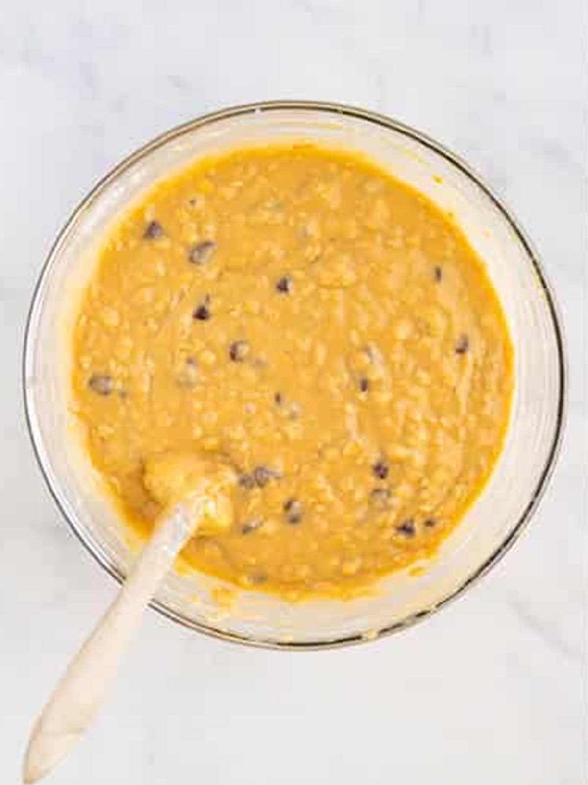 Chocolate chip oatmeal muffin batter mixed in a glass bowl.