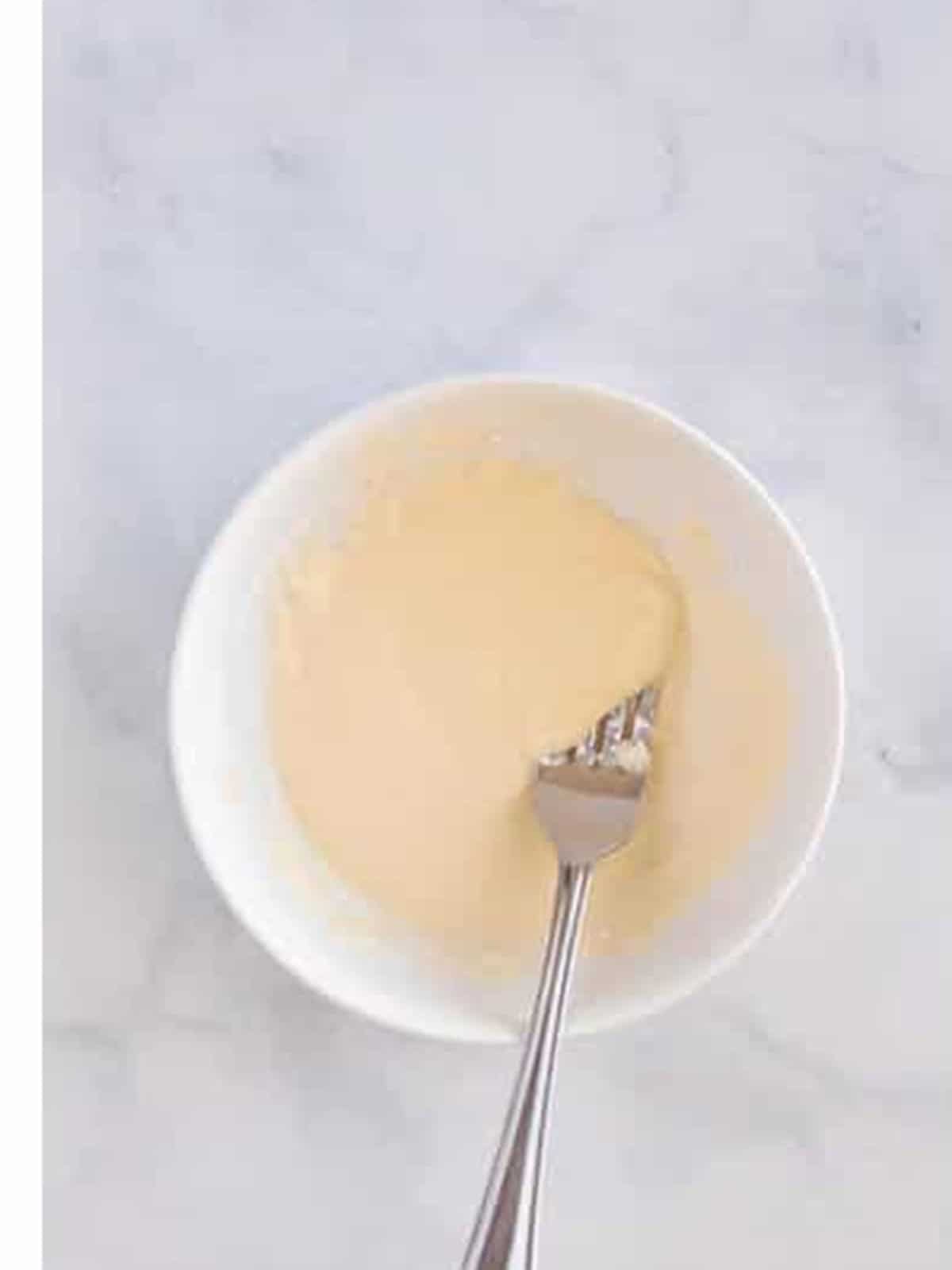 Maple glaze whisked in a small bowl for oatmeal muffins.