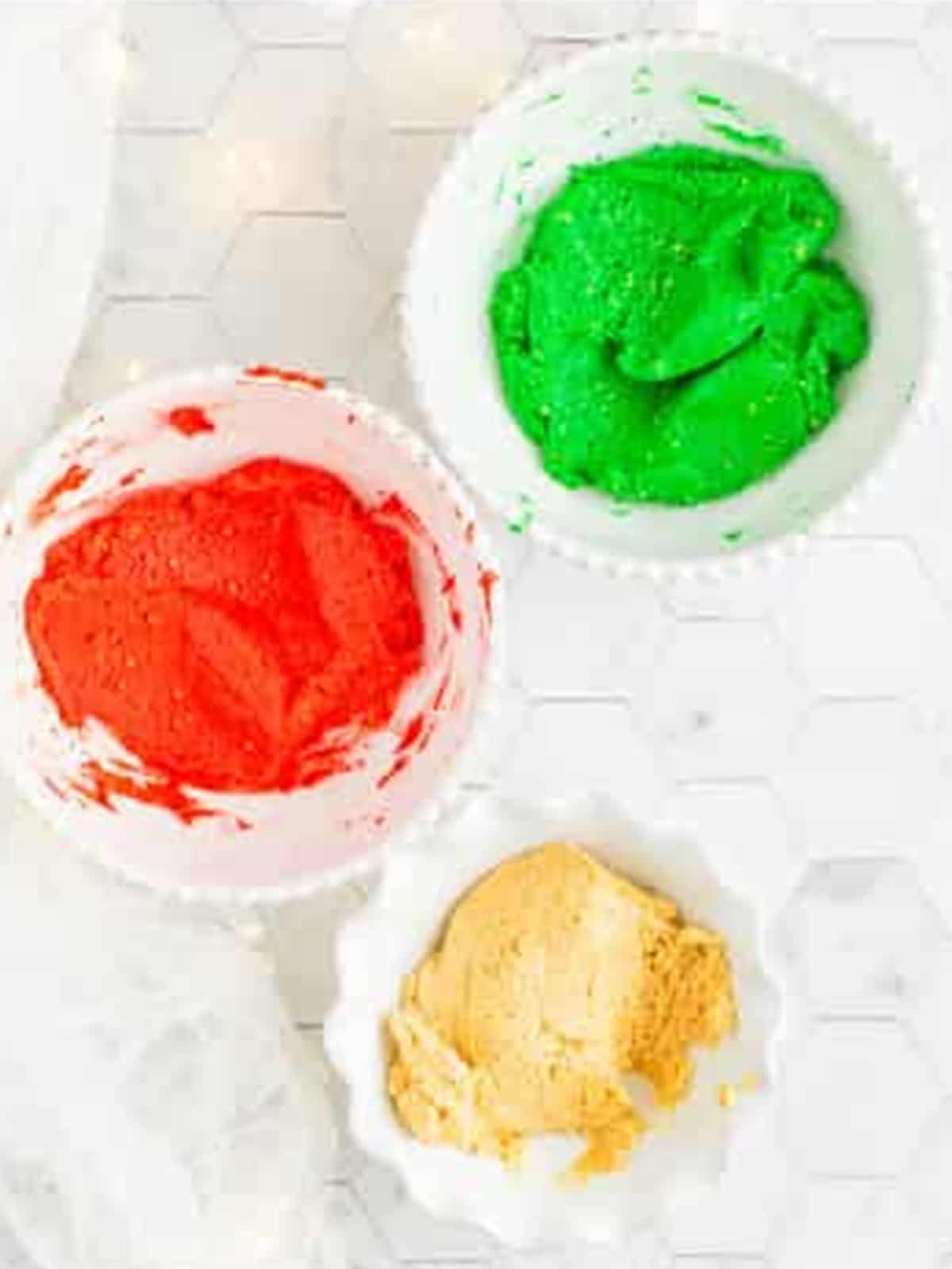 Oreo Balls mixture divided into three bowls with red and green food coloring.