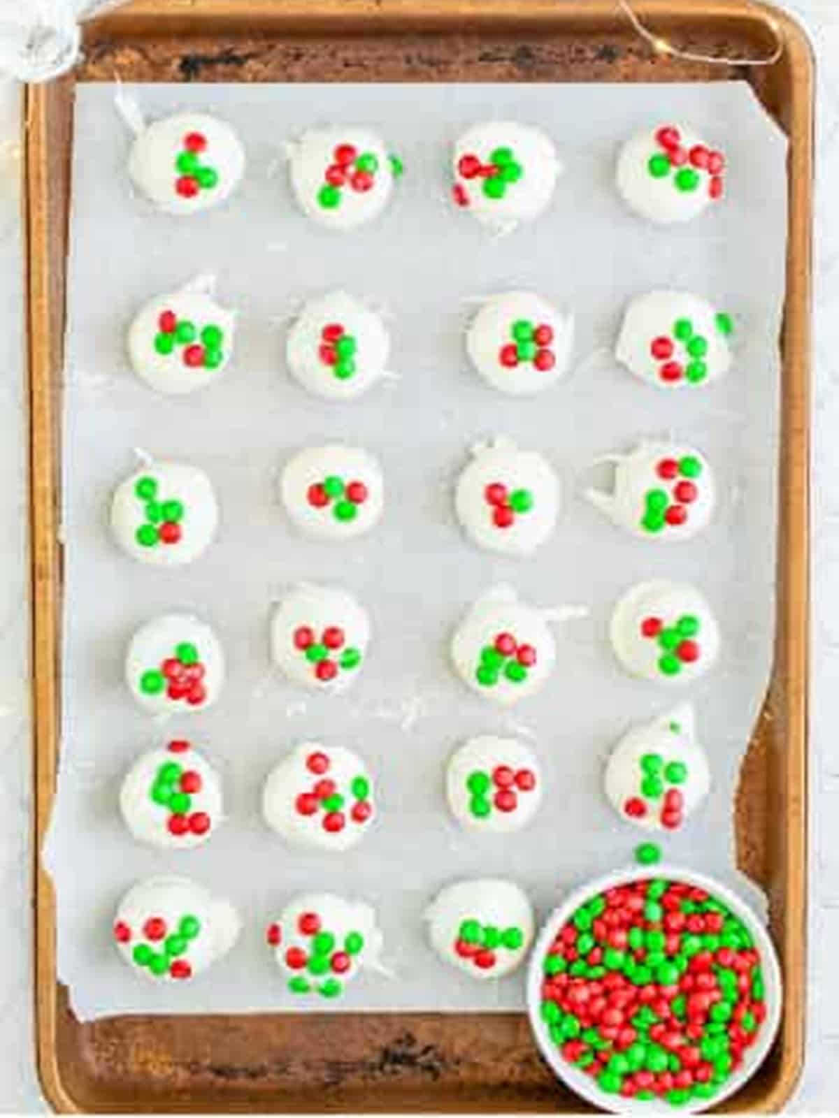Dipped Oreo Balls topped with mini holiday M and Ms on a sheet tray.