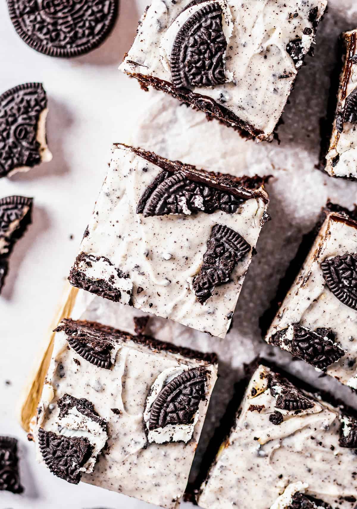 Oreo Brownies cut into squares showing the white Oreo fudge topping and whole Oreos.