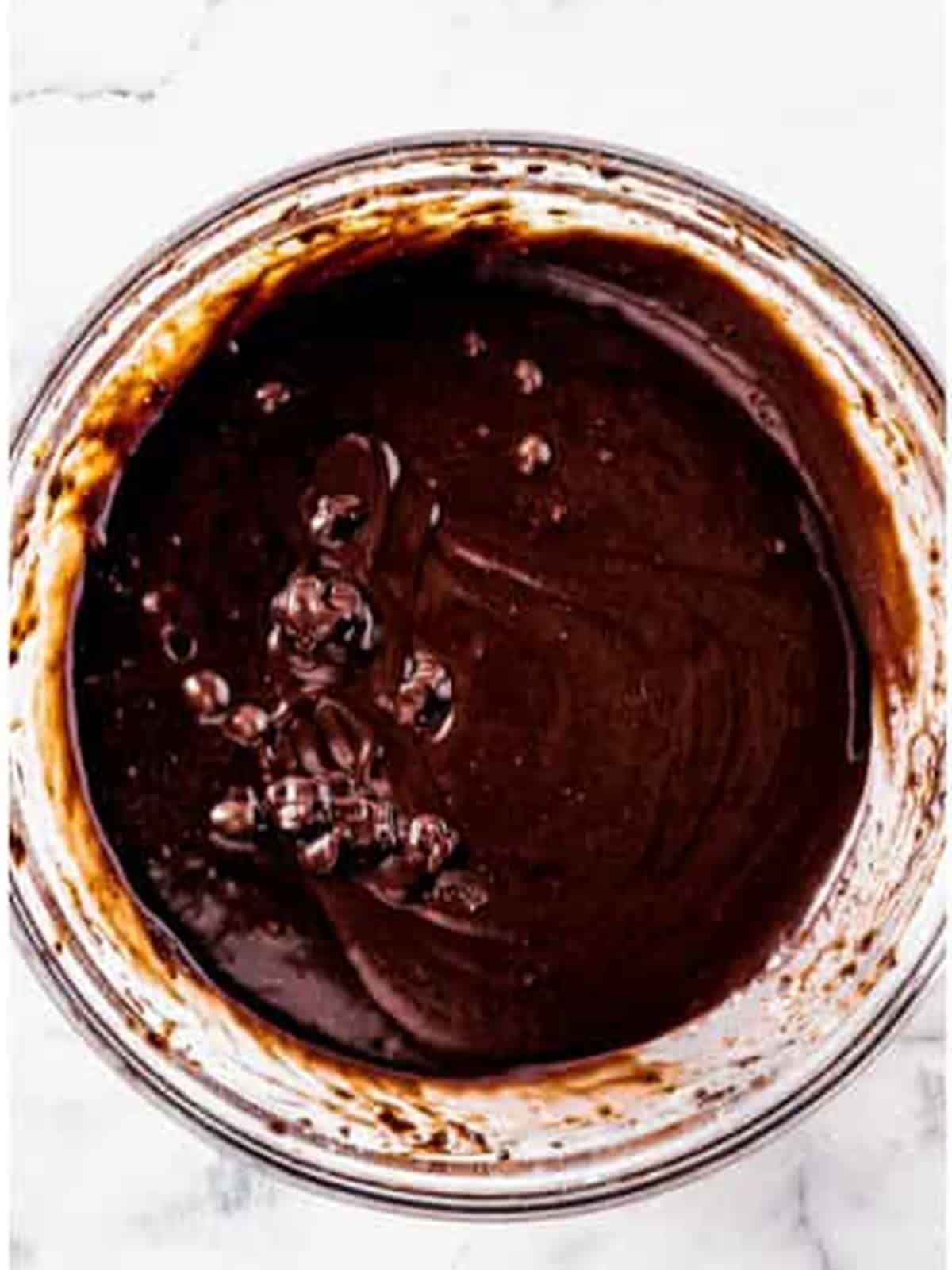 Mixing fudge brownie batter with eggs, water, and melted butter in a glass bowl for Oreo Brownies.