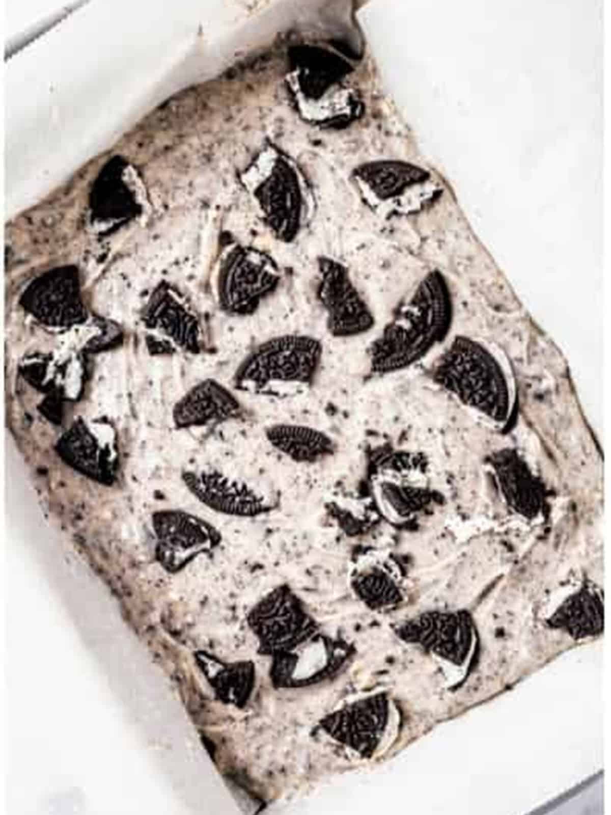 Oreo fudge topping spread over cooled brownies and topped with crumbled Oreos before chilling.