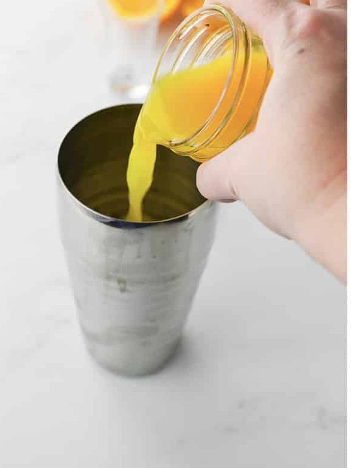 Pouring fresh orange juice into the cocktail shaker for the painkiller.