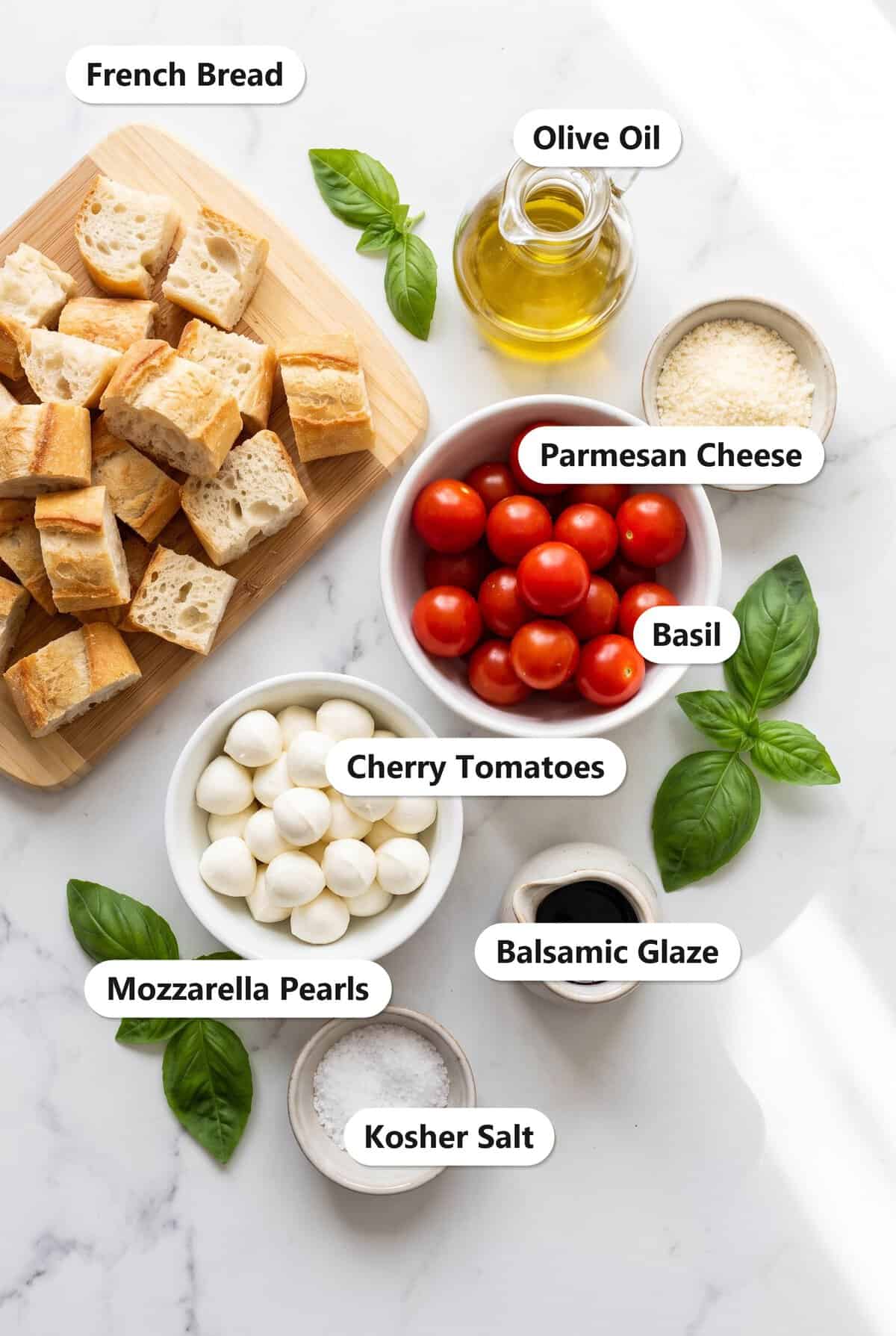 Labeled ingredients for Panzanella including french bread, cherry tomatoes, mozzarella pearls, basil, olive oil, parmesan cheese, balsamic glaze, and kosher salt.