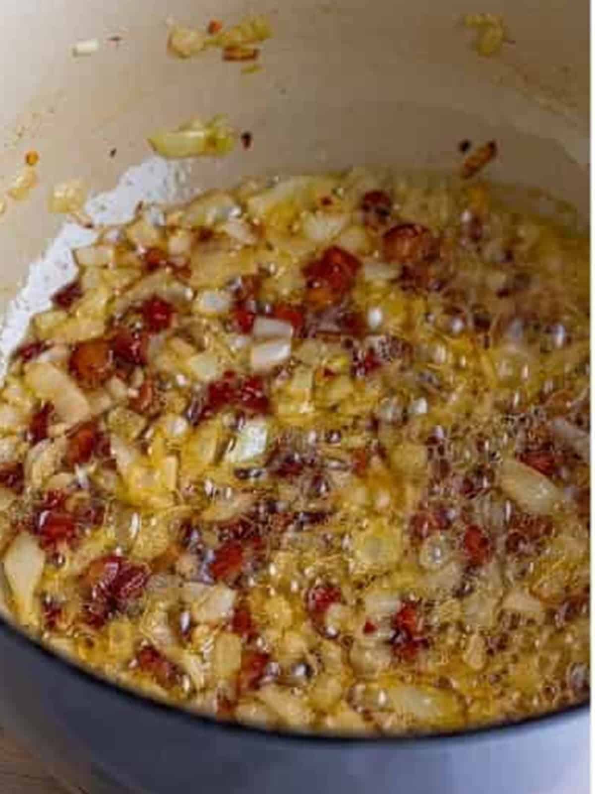 Diced guanciale crisping in olive oil in a Dutch oven for Pasta Amatriciana.