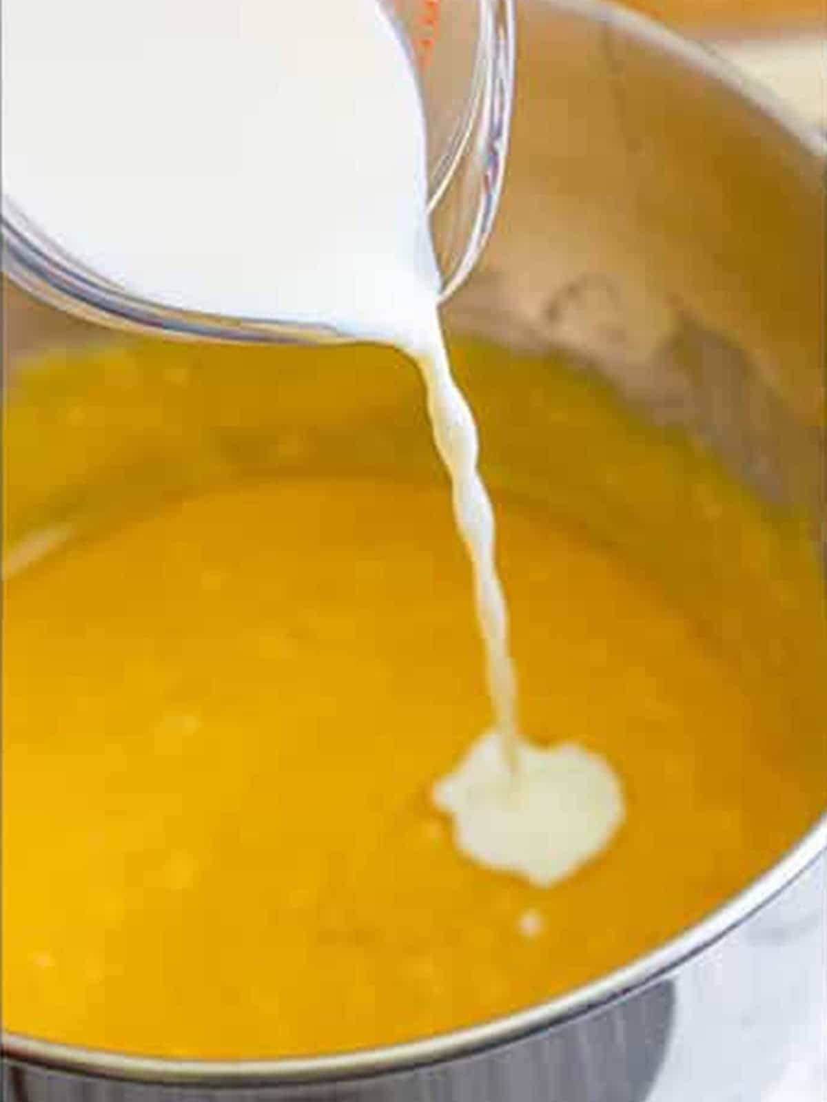Milk being poured into the peach cake batter