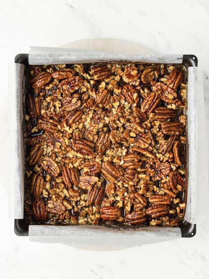 Maple pecan topping poured over the baked brownie layer ready to go back in the oven.