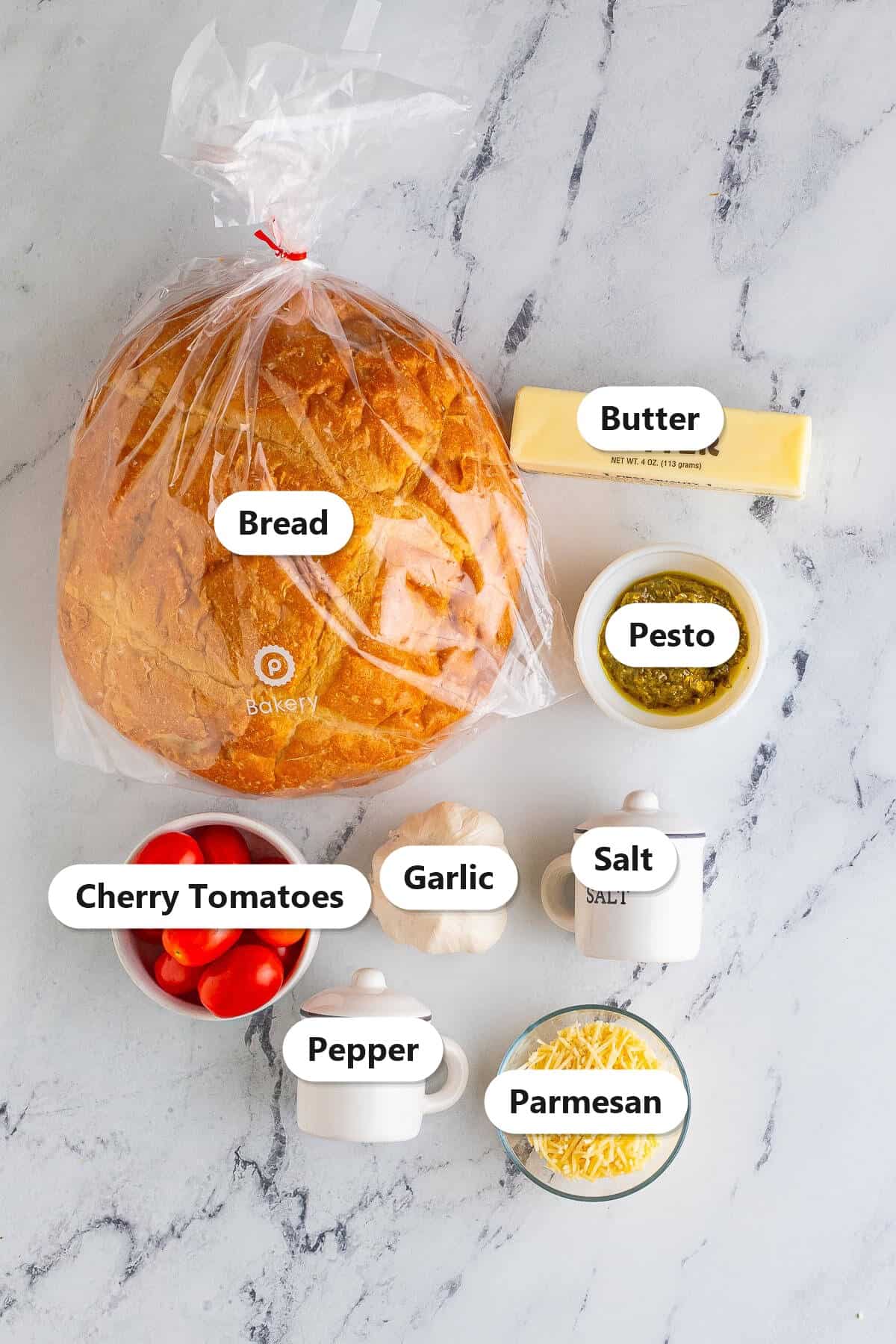 Labeled ingredients for Pesto Toast including rustic bread, butter, pesto, cherry tomatoes, garlic, and parmesan.