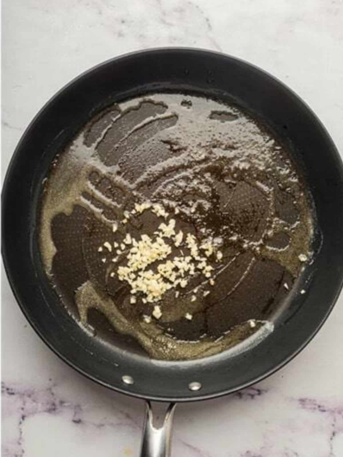 Sauteing minced garlic in butter in a skillet until fragrant.