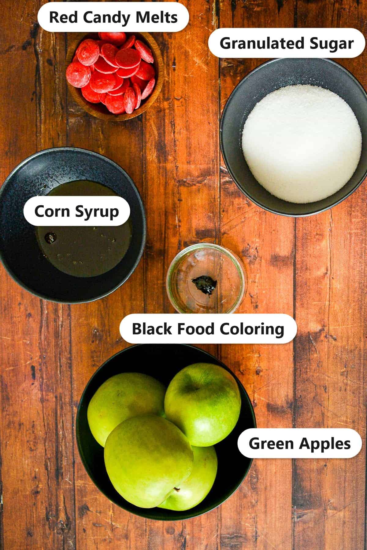Labeled ingredients for poison apples including green apples, granulated sugar, corn syrup, black food coloring, and red candy melts.