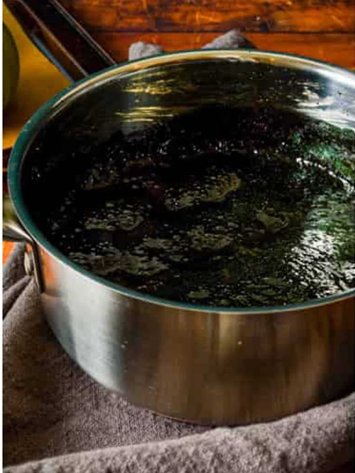 Black candy syrup for poison apples cooking in a saucepan to 300 degrees.