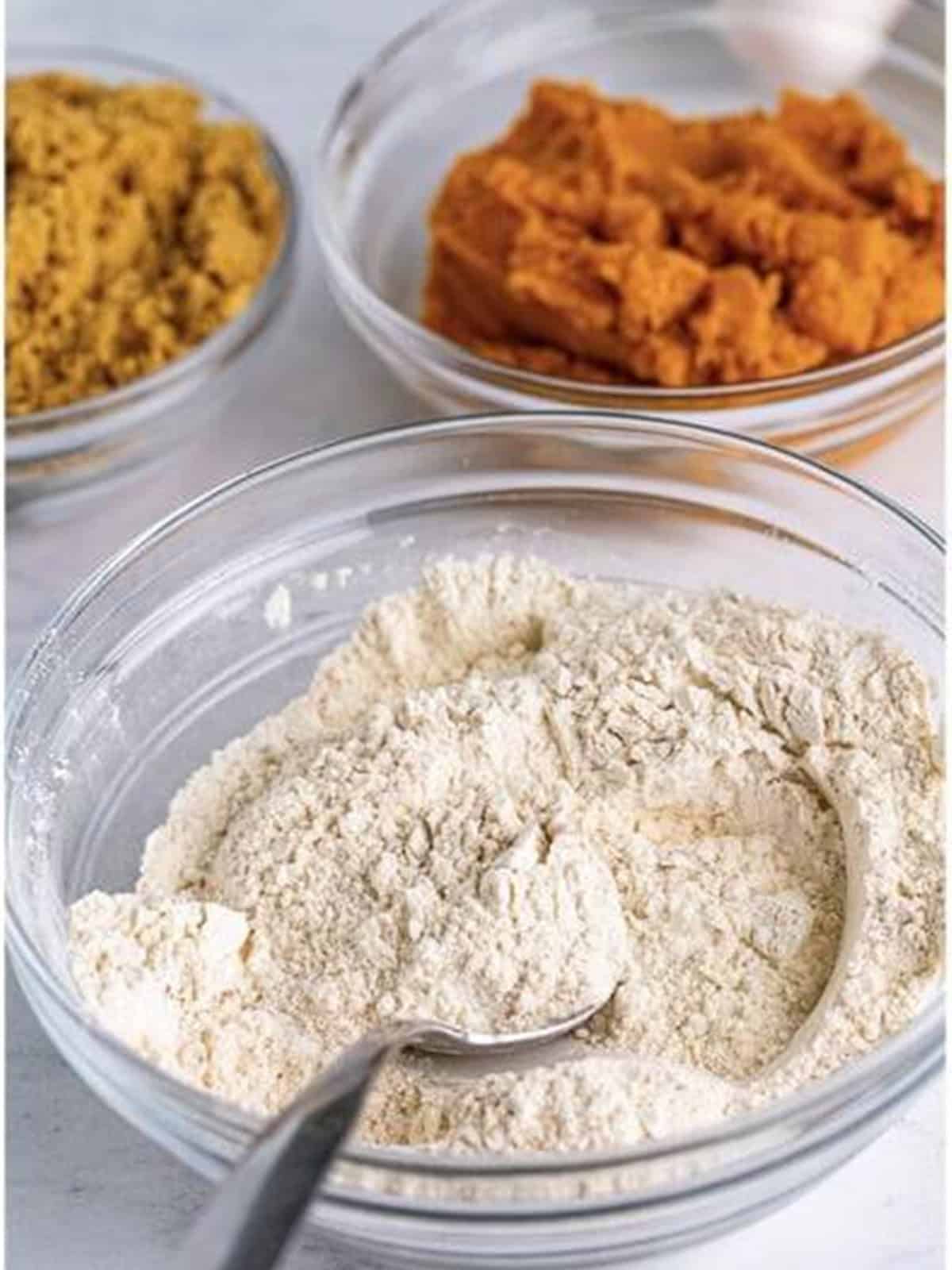 Flour, baking soda, pumpkin pie spice, and salt stirred together in a glass bowl for Pumpkin Cake.