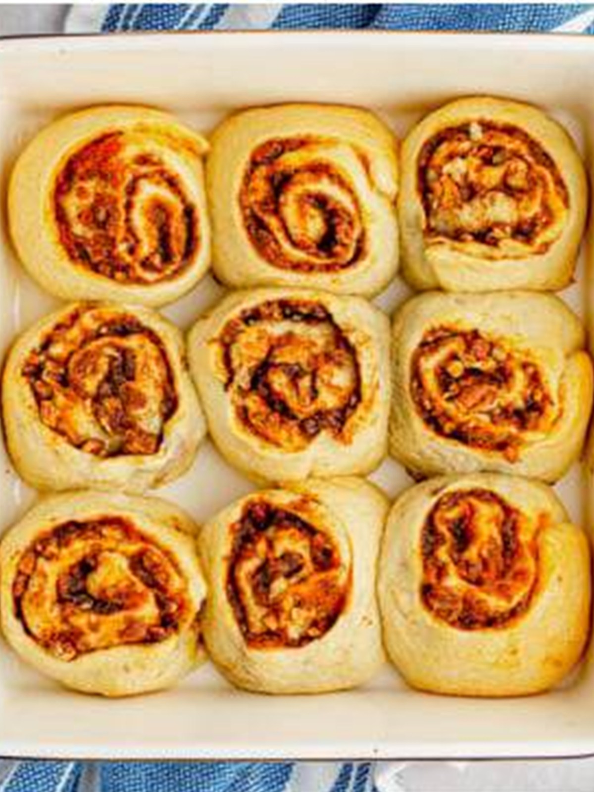 Baked pumpkin cinnamon rolls golden brown in a baking dish.