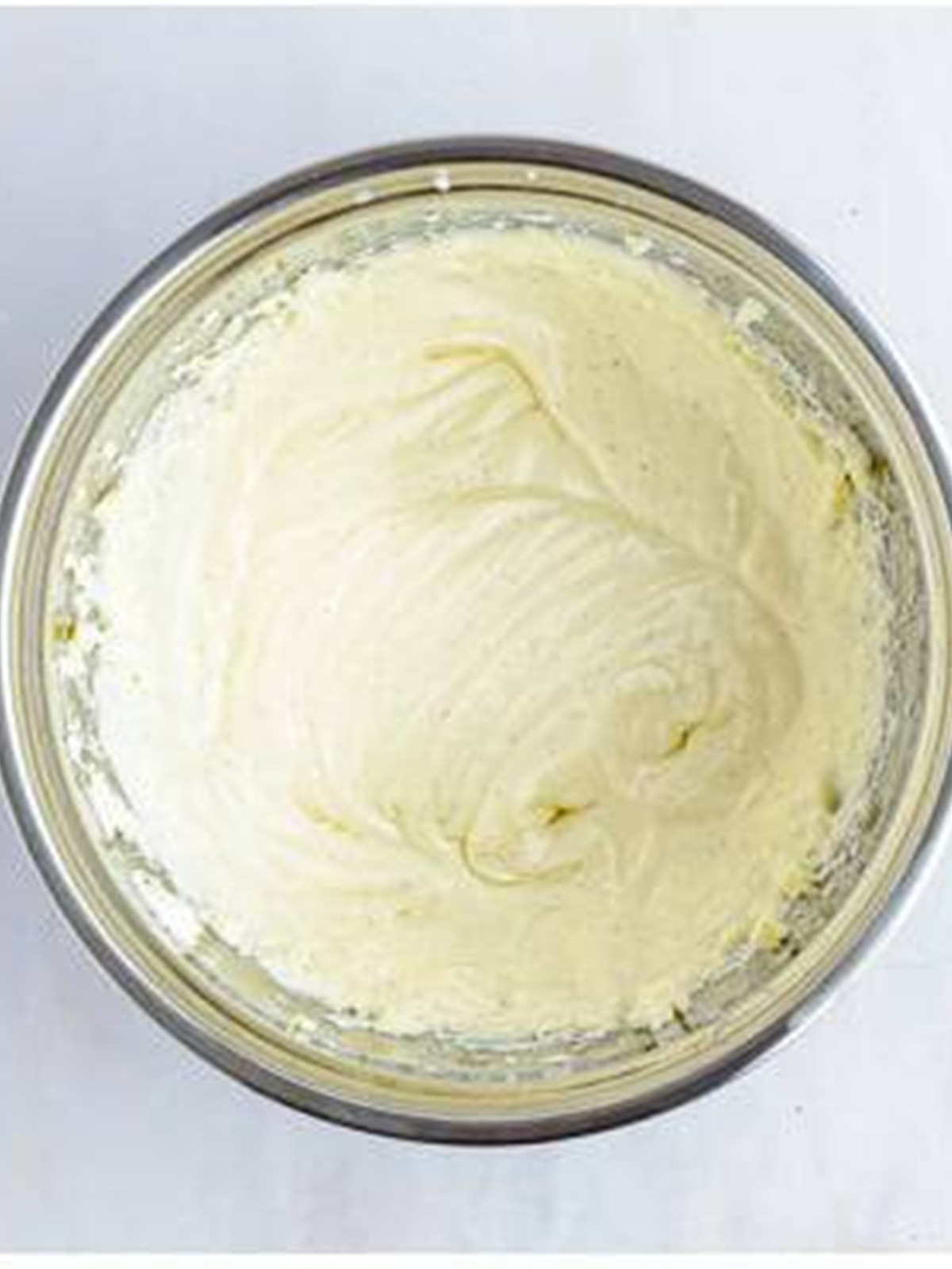 Cream cheese frosting whipped smooth in a mixing bowl.