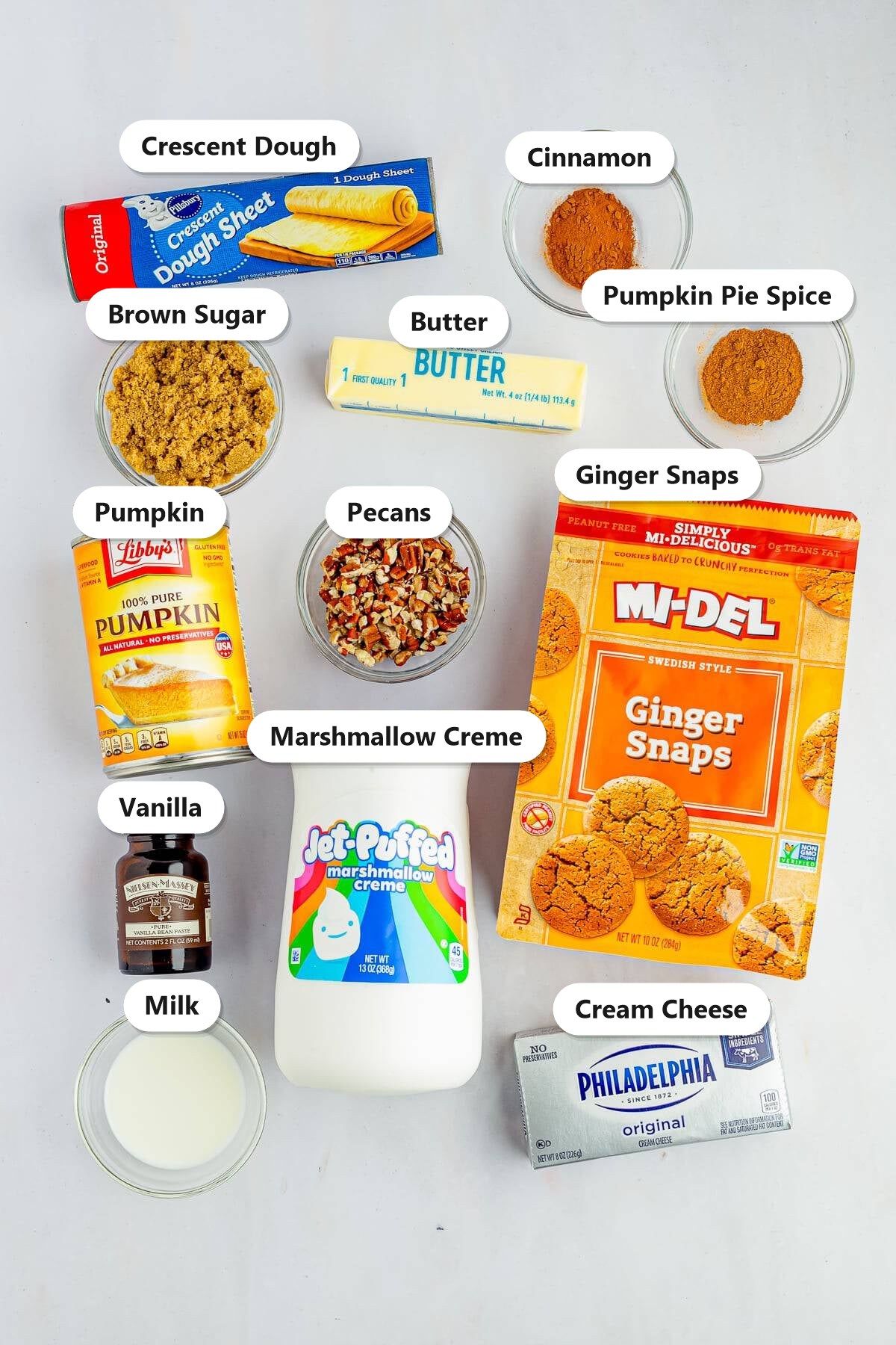 Labeled ingredients for pumpkin cinnamon rolls including crescent dough, pumpkin, brown sugar, cinnamon, pecans, and cream cheese.