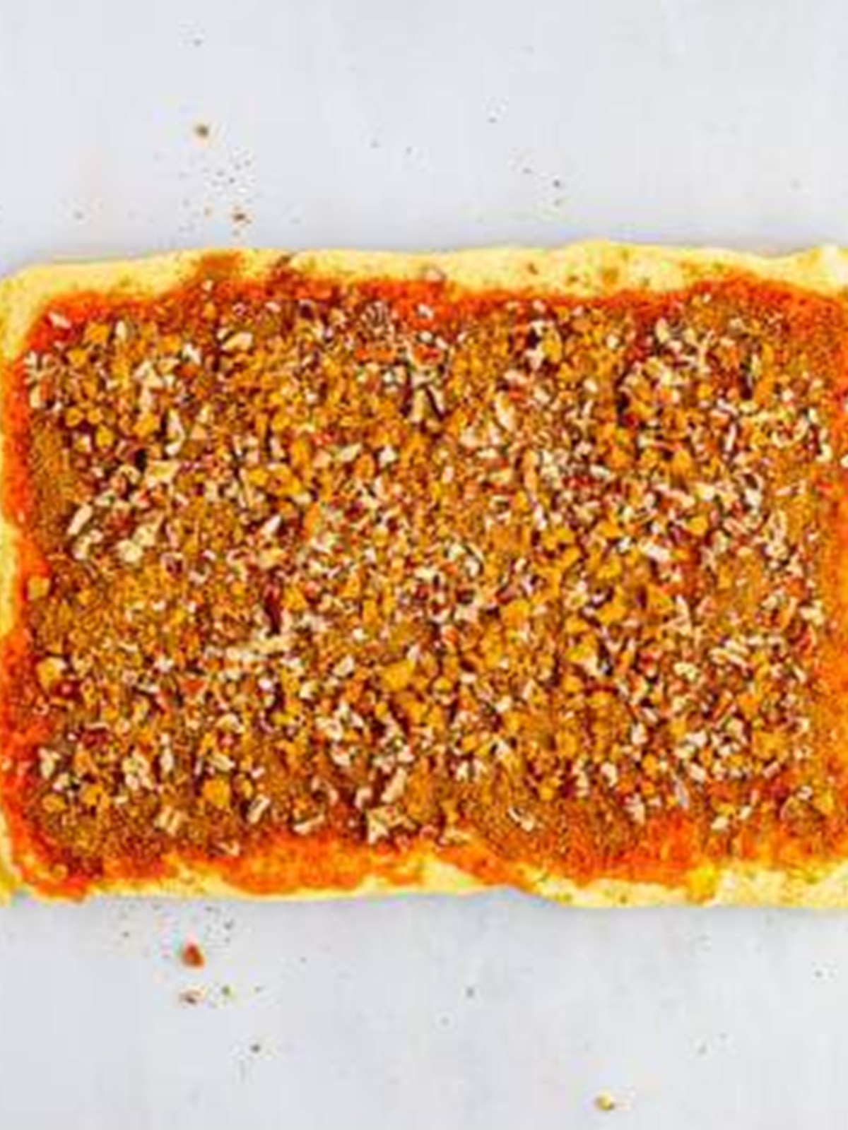 Pumpkin filling and chopped pecans spread over rolled out crescent dough.