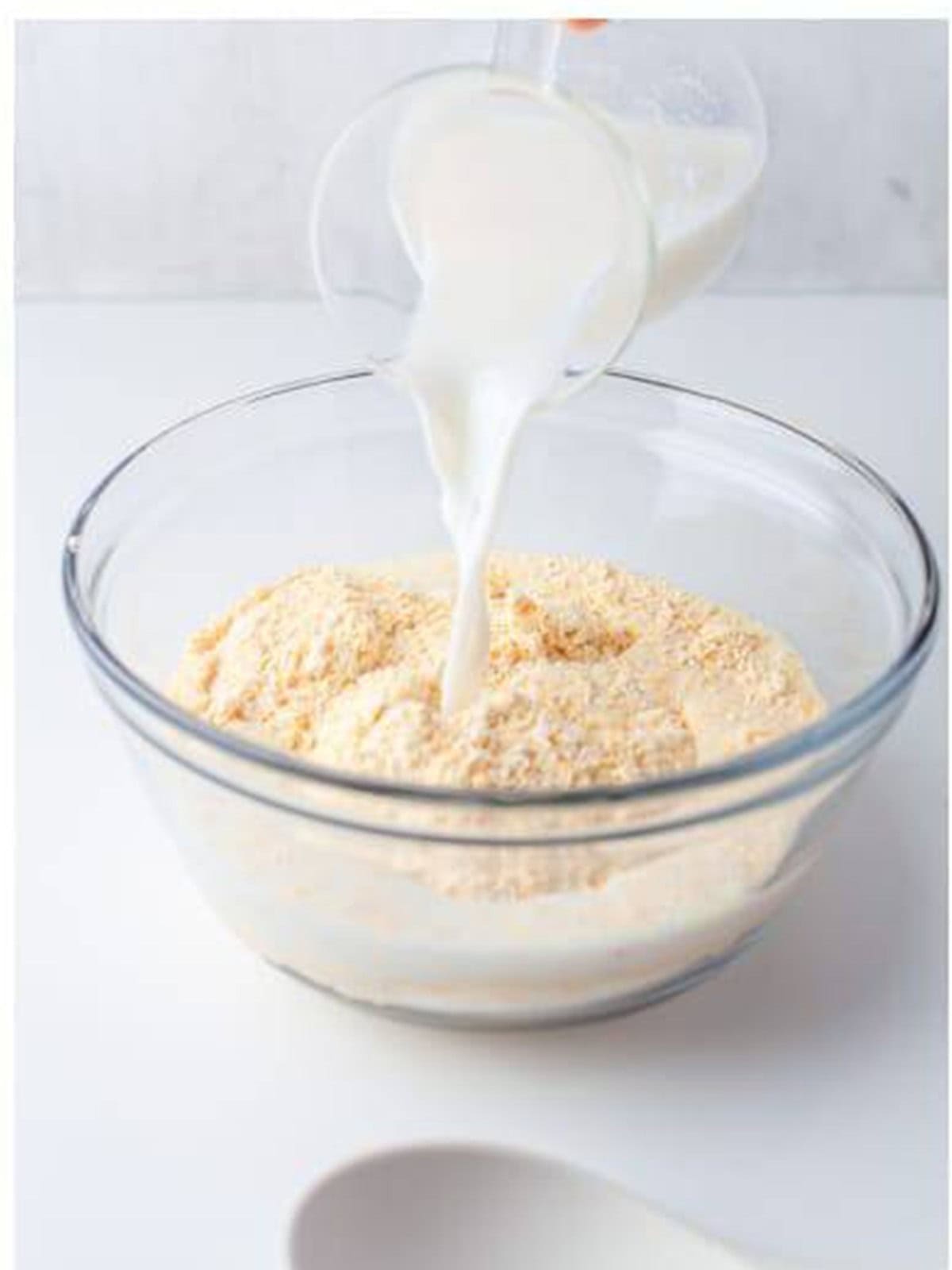 Buttermilk poured over cornmeal in a glass bowl to soak.