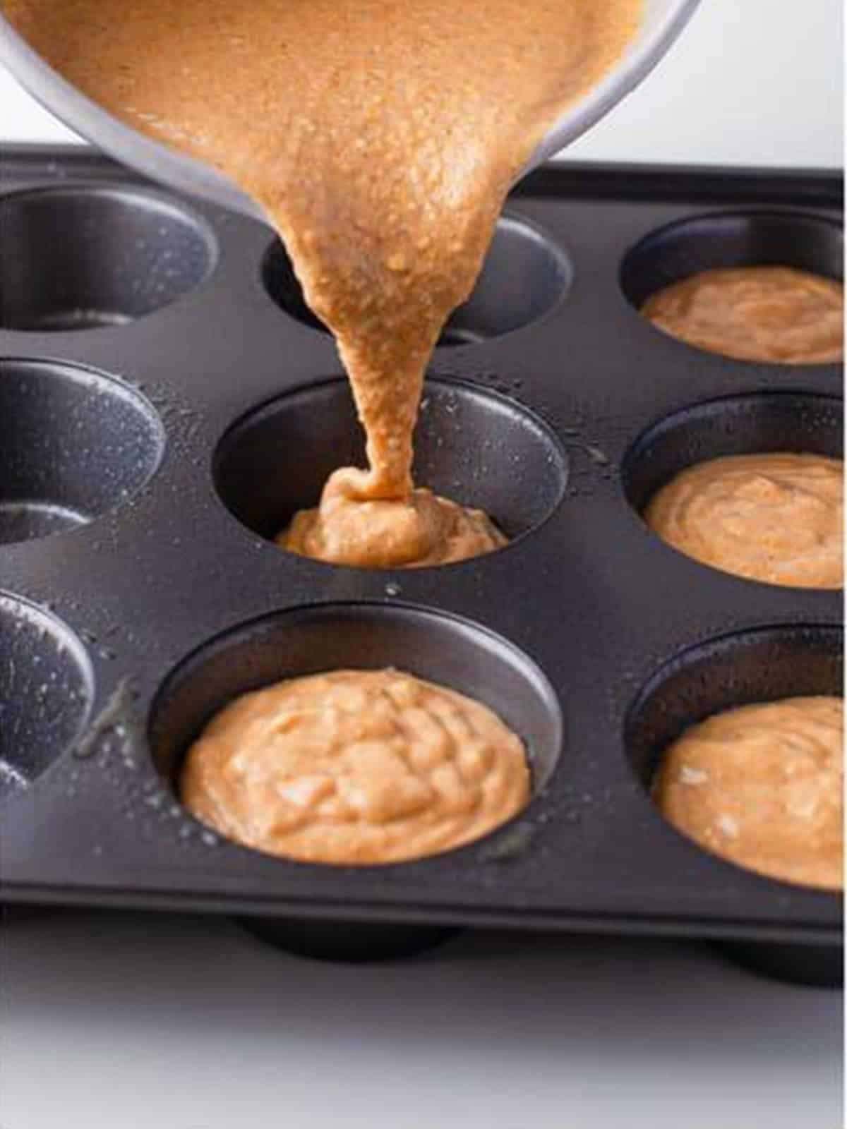 Pumpkin Cornbread batter divided into a muffin tin.