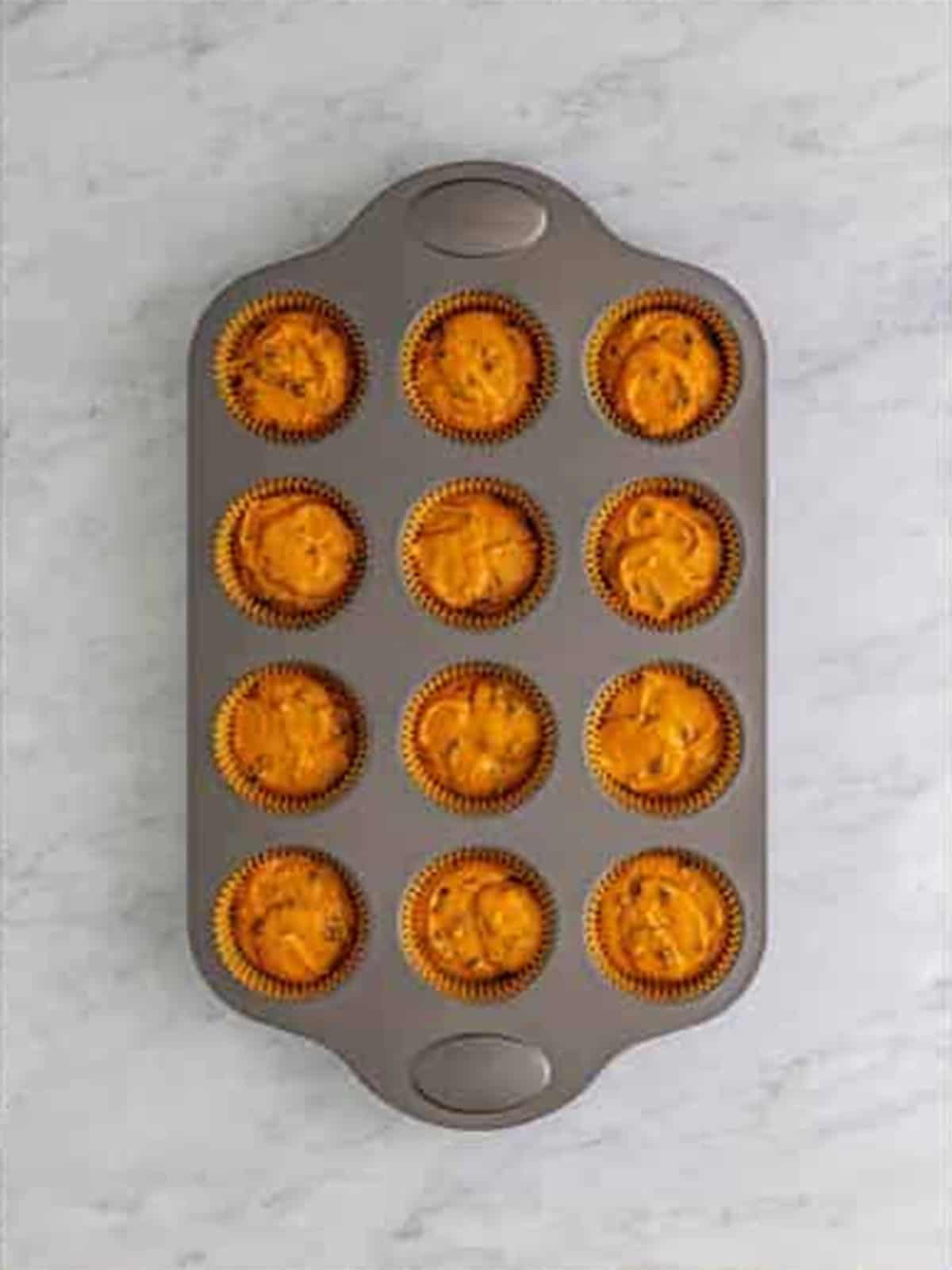 Pumpkin cupcake batter divided among liners in a cupcake tin ready to bake.