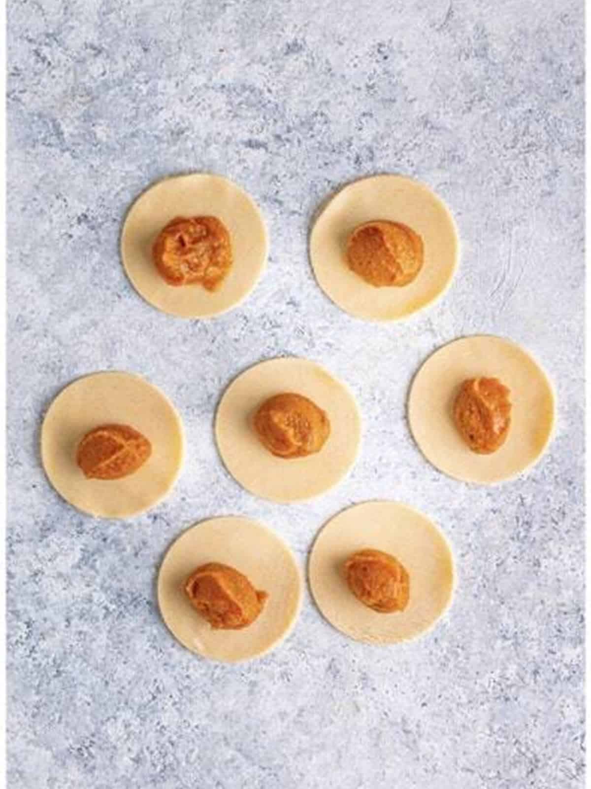 Pumpkin filling spooned onto the centers of the dough circles.
