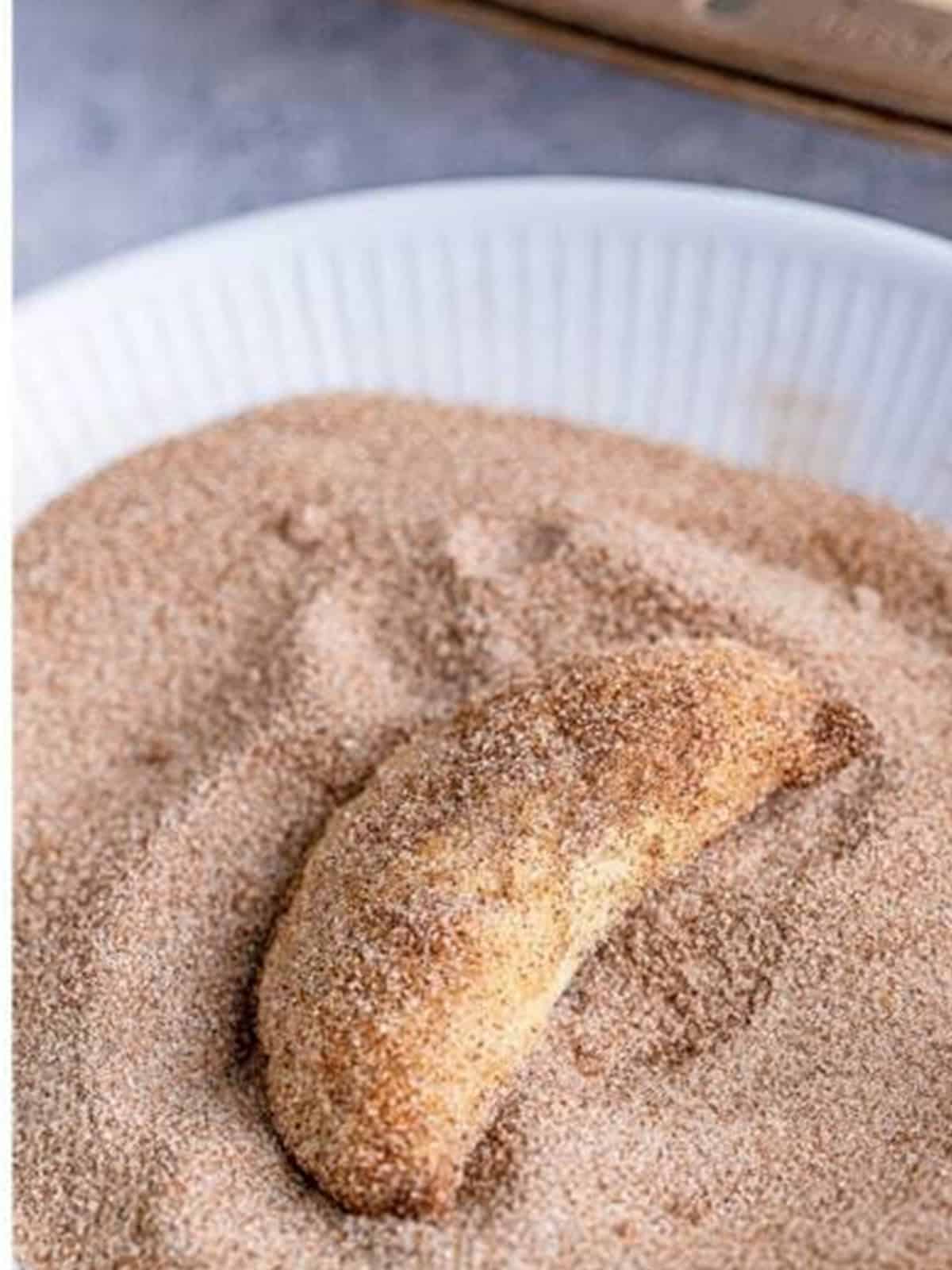 A warm pumpkin hand pie being coated in cinnamon sugar.