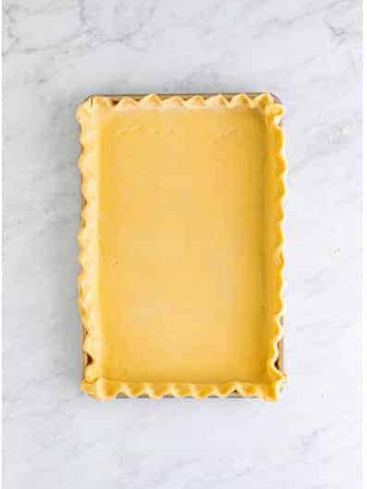 Pie crust fitted into a jelly roll pan with crimped edges for pumpkin slab pie.