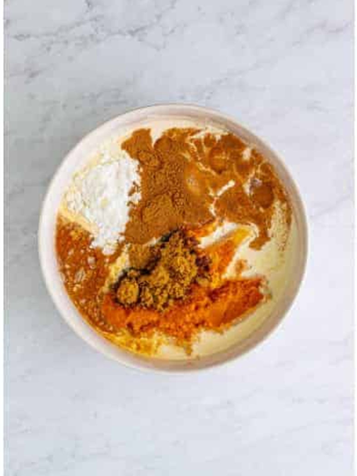 Pumpkin puree, brown sugar, cream, eggs, and spices in a large mixing bowl for pumpkin slab pie filling.
