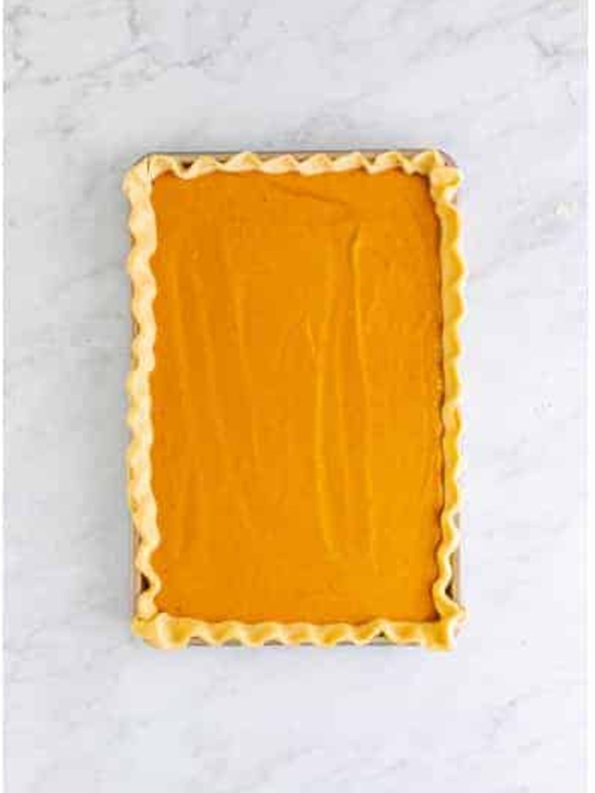 Pumpkin pie filling poured into the crust lined jelly roll pan and smoothed out.