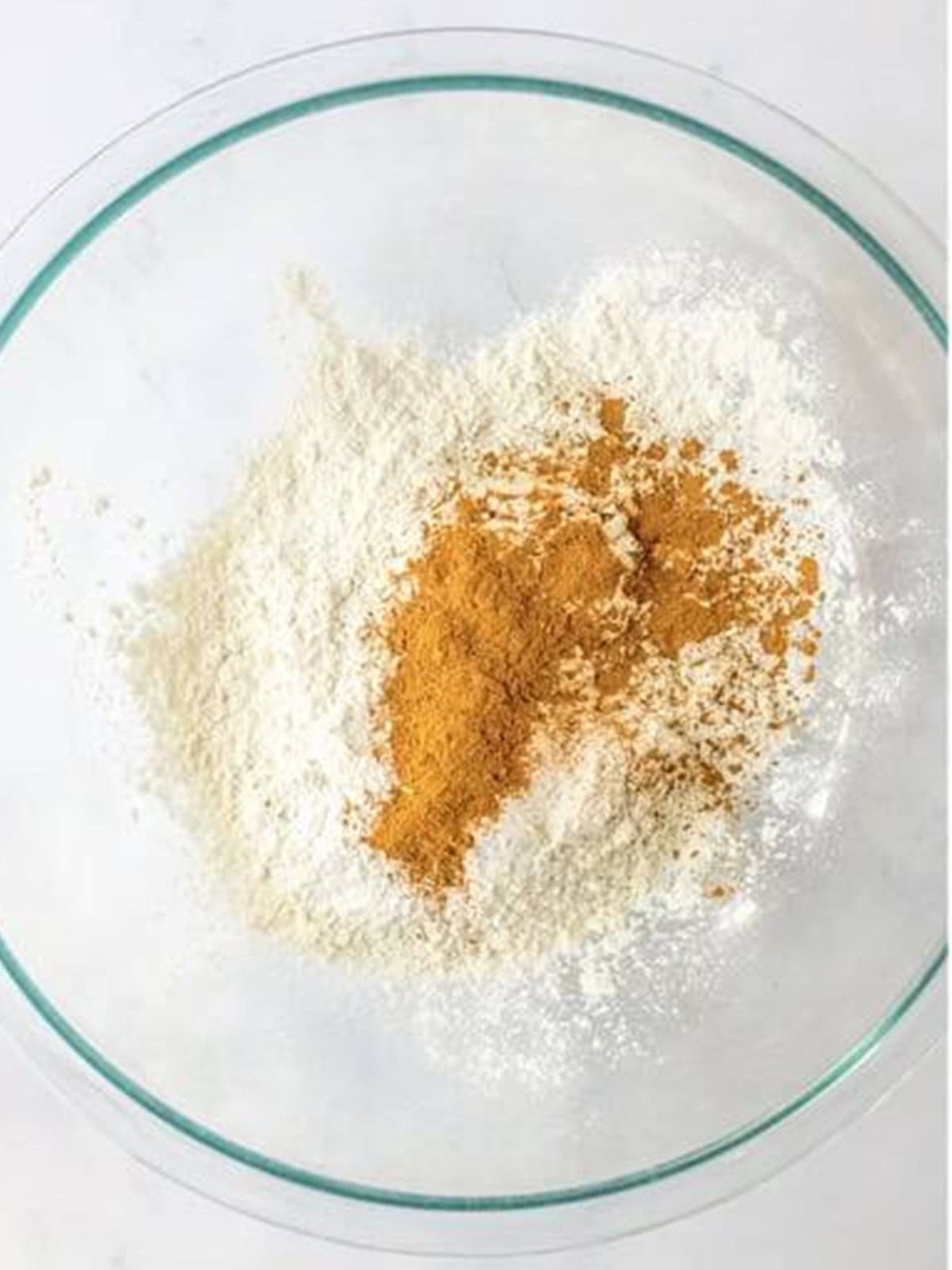 Flour, cinnamon, and pumpkin pie spice in a glass bowl for the dry mix.