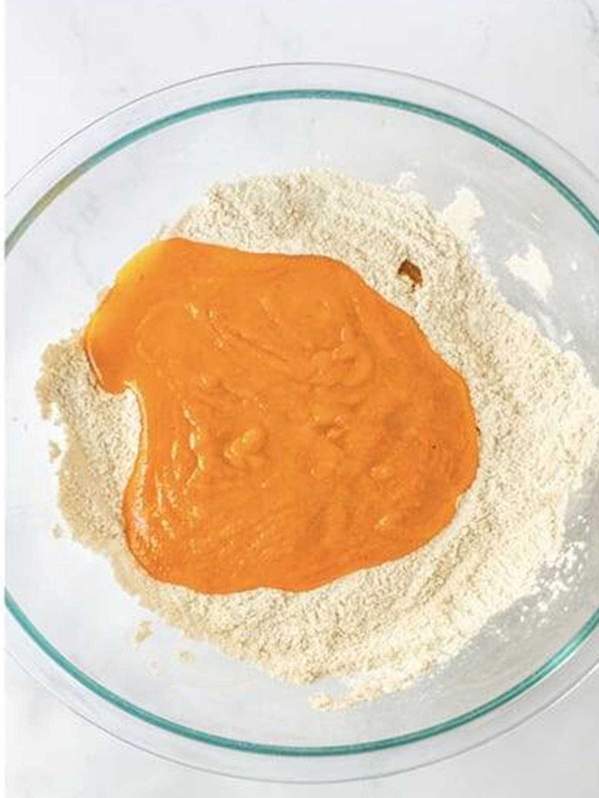 Wet ingredients poured into the dry ingredients for Pumpkin Snickerdoodles dough.