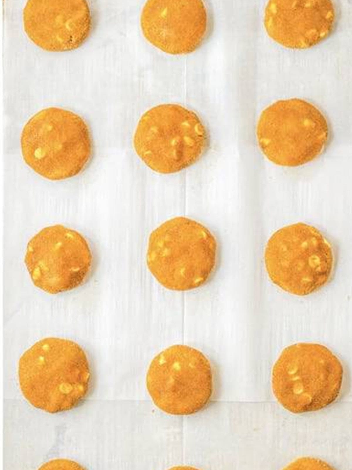 Cinnamon sugar coated Pumpkin Snickerdoodles dough balls on a parchment lined baking sheet.