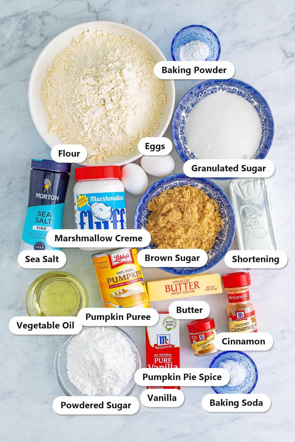 Labeled ingredients to make Pumpkin Whoopie Pies: flour, pumpkin puree, sugars, eggs, butter, shortening, marshmallow creme, spices, and vanilla.