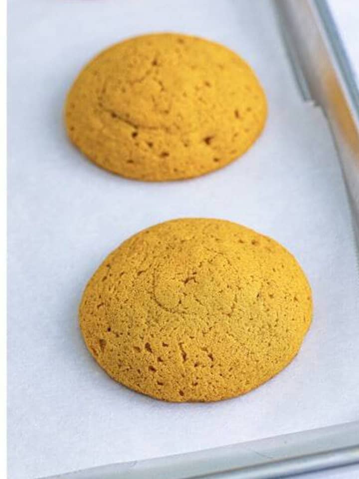 Baked Pumpkin Whoopie Pies cookie rounds cooling on the baking sheet.