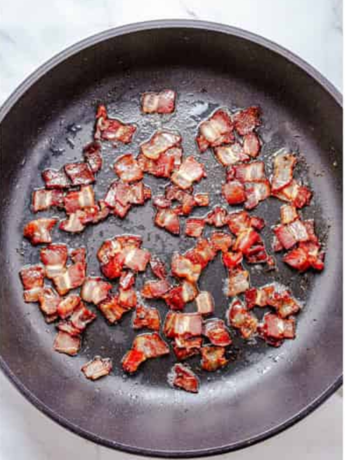 Diced bacon cooked until crispy in a skillet for Ranch Potato Salad.