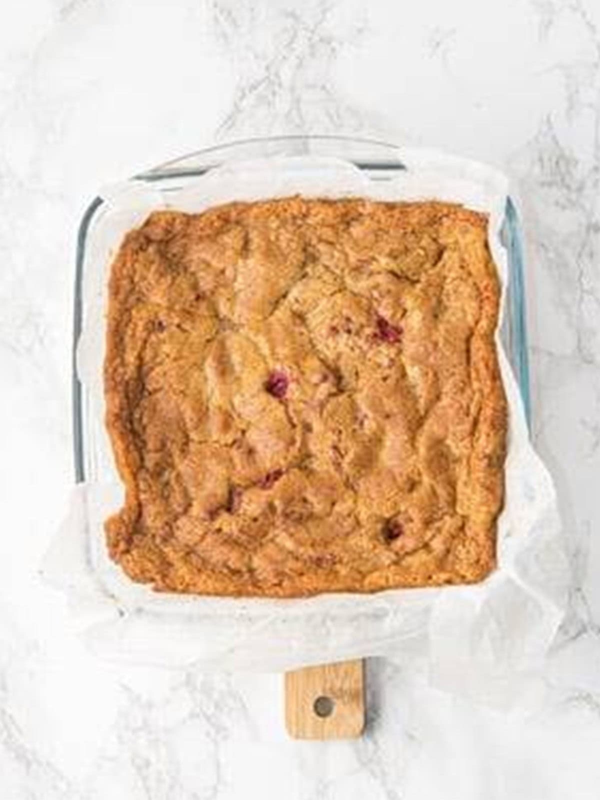 Baked raspberry brownies with a golden top cooling in the pan.