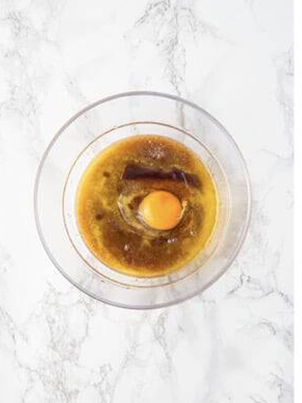 Melted butter, brown sugar, vanilla, and egg in a glass bowl for raspberry brownies.