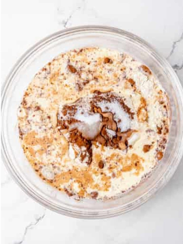 Wet ingredients added to the dry pancake mix in a glass bowl.