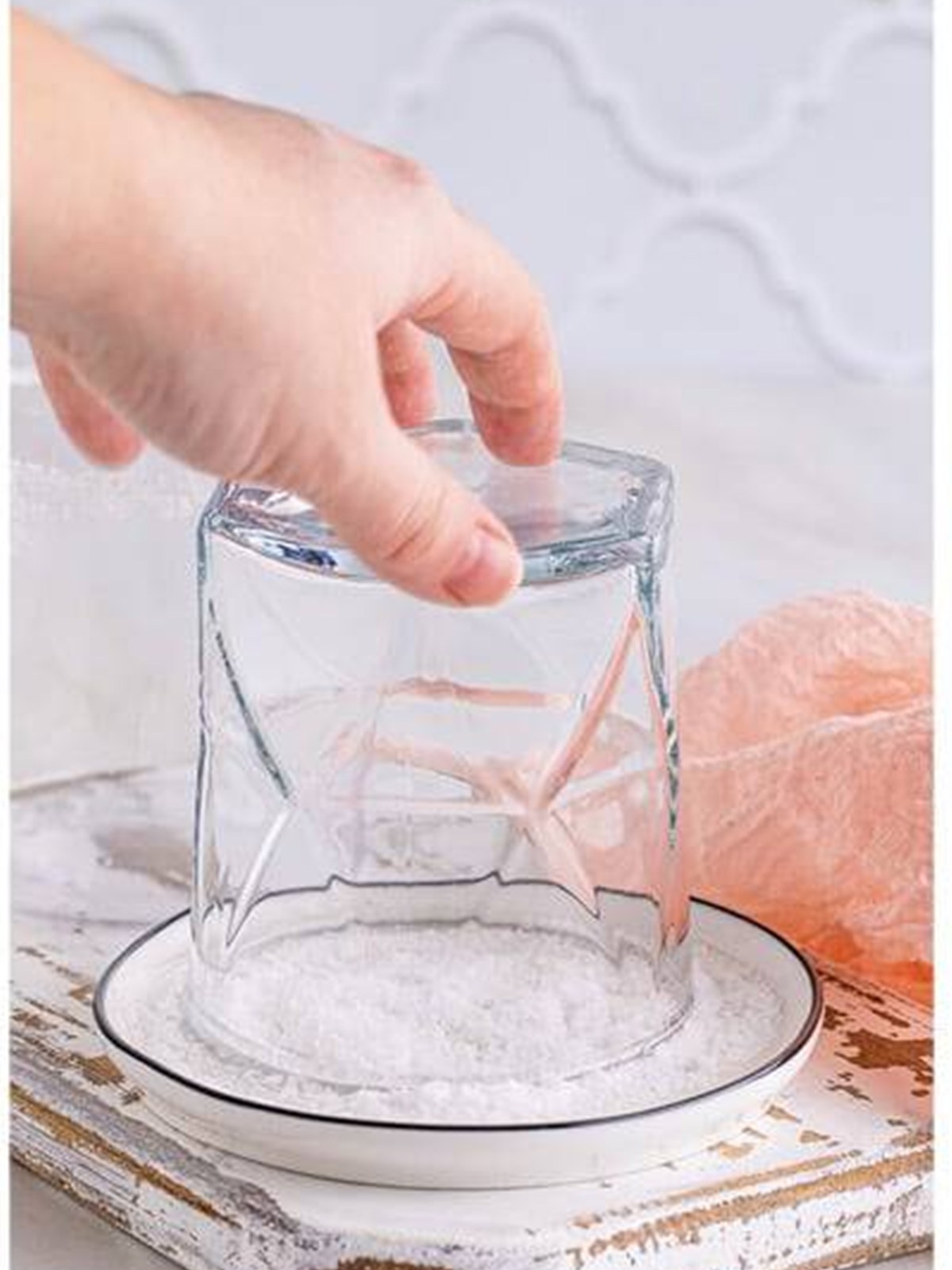 Dipping the grapefruit-rimmed glass into a plate of kosher salt.