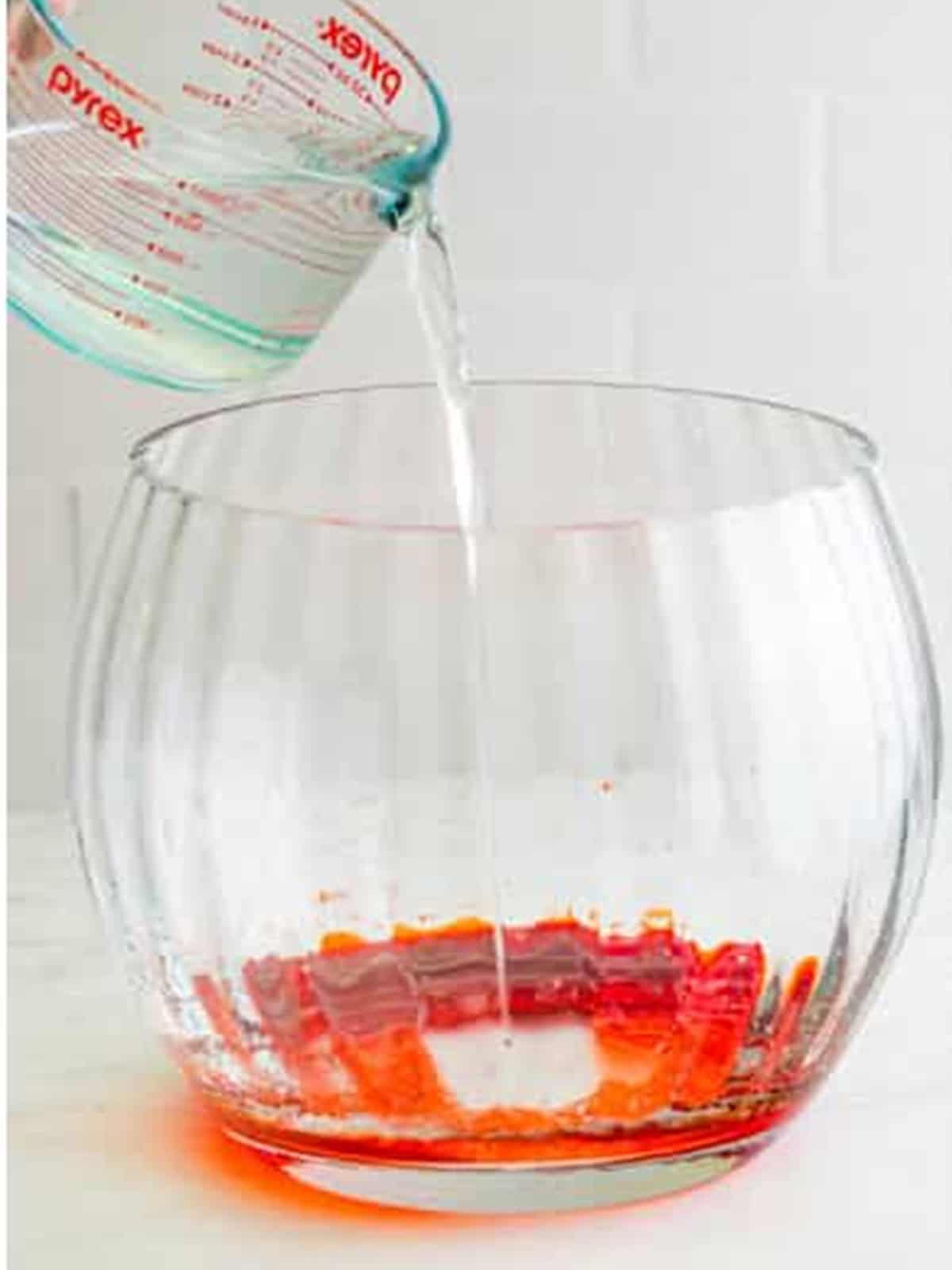 Water poured over strawberry drink mix in a punch bowl for Sherbet Punch.