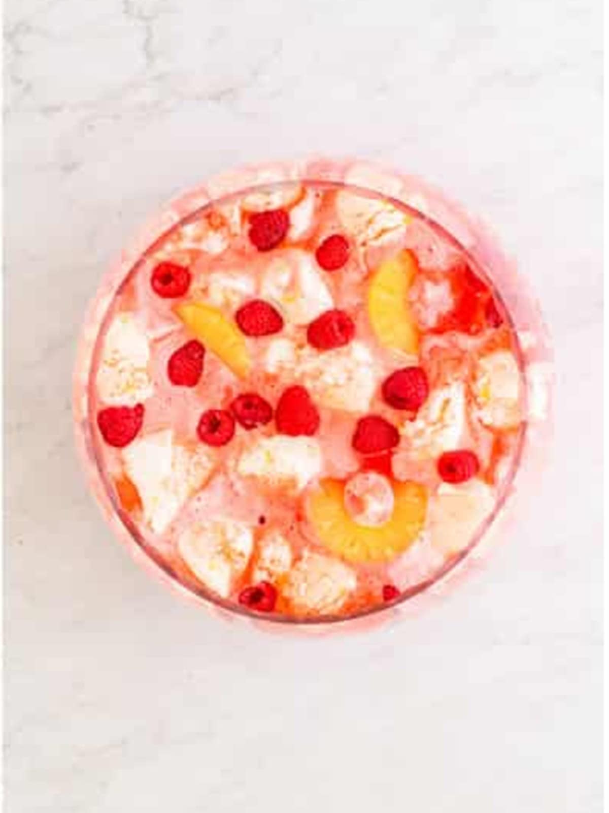 Sherbet Punch garnished with pineapple rings and fresh raspberries ready to serve.