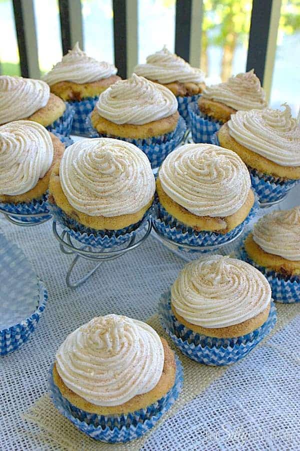 Snickerdoodle cupcakes topped with cinnamon cream cheese frosting and cinnamon sugar on a cupcake stand.