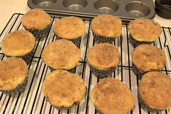 Snickerdoodle cupcakes tops dipped in cinnamon sugar on a wire rack.